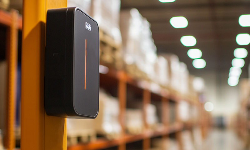 Ein RFID-Lesegerät in einem Lagerhaus, montiert an einem Gelbpfosten, zur Optimierung von Bestandsmanagement und Zugangskontrolle.
